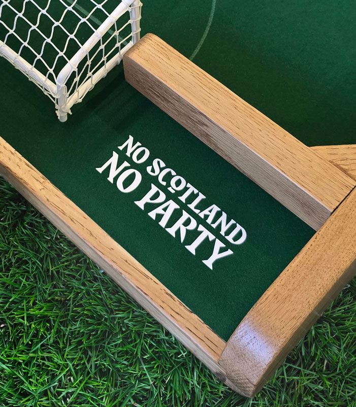 A close up of a FlickForKicks oak indoor arena with No Scotland No Party printing on the pitch
